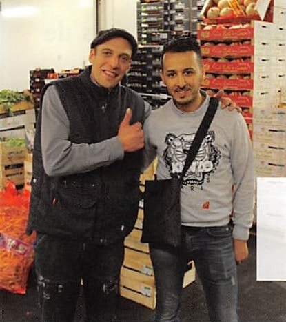 deux hommes devant des cageots de fruits et légumes